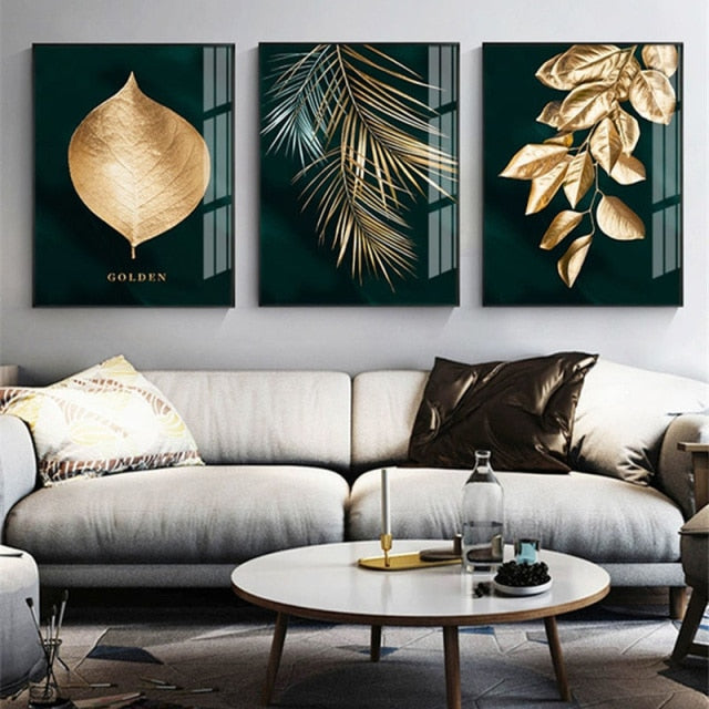 Three contemporary gold and turquoise leaf wall art prints hanging above a sofa