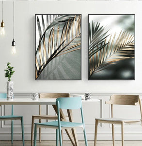 Two nordic golden palm leaf wall art prints hanging above a table and chairs