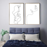 Load image into Gallery viewer, Two black and white single line lady face wall art prints above blue bed

