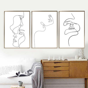 Three black and white single line lady face wall art prints above sofa and sideboard