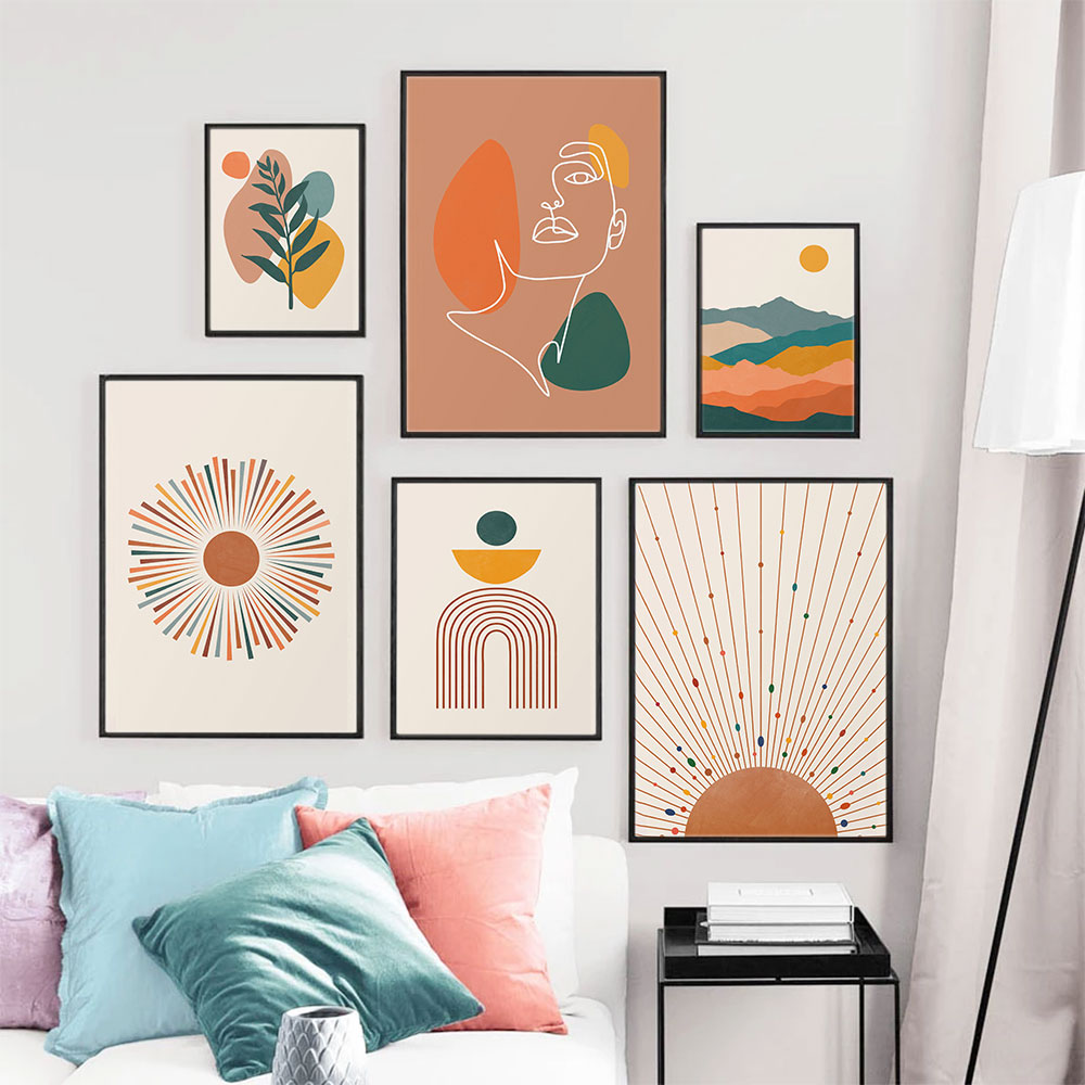 Gallery wall of six pictures made up of a white line drawing of a female face a colourful mountain range with an orange sun and a green leaf frond sun rise wall art prints